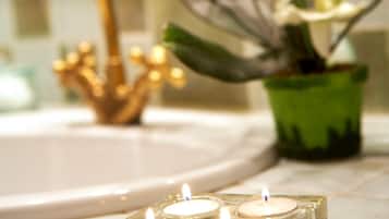 A bathroom with a sink, a gold faucet, and a green vase with white flowers.