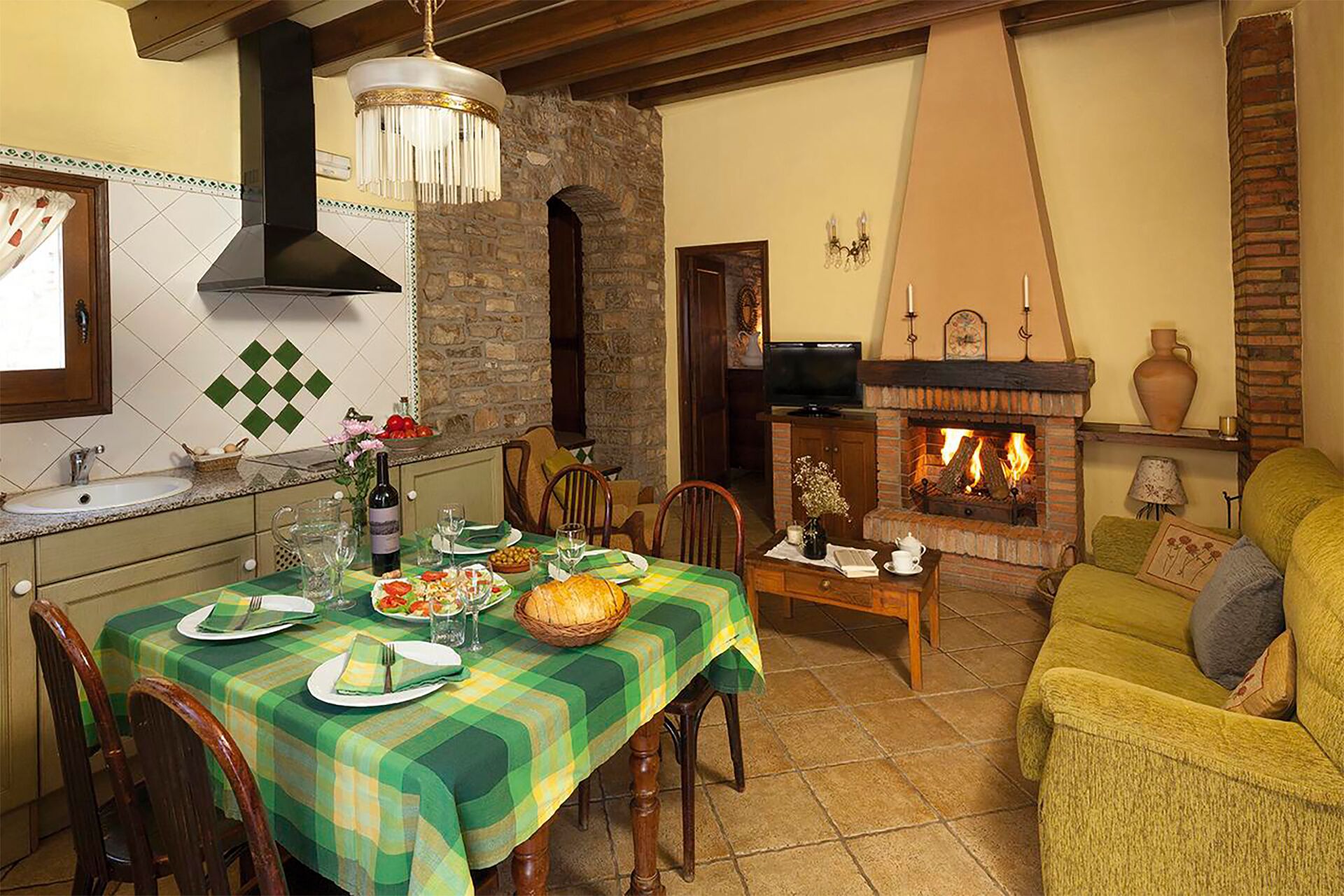 Comedor con una mesa dispuesta para cuatro, chimenea y televisión al fondo.