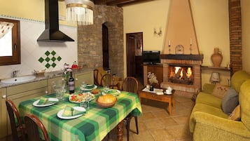 Comedor con una mesa dispuesta para cuatro, chimenea y televisión al fondo.