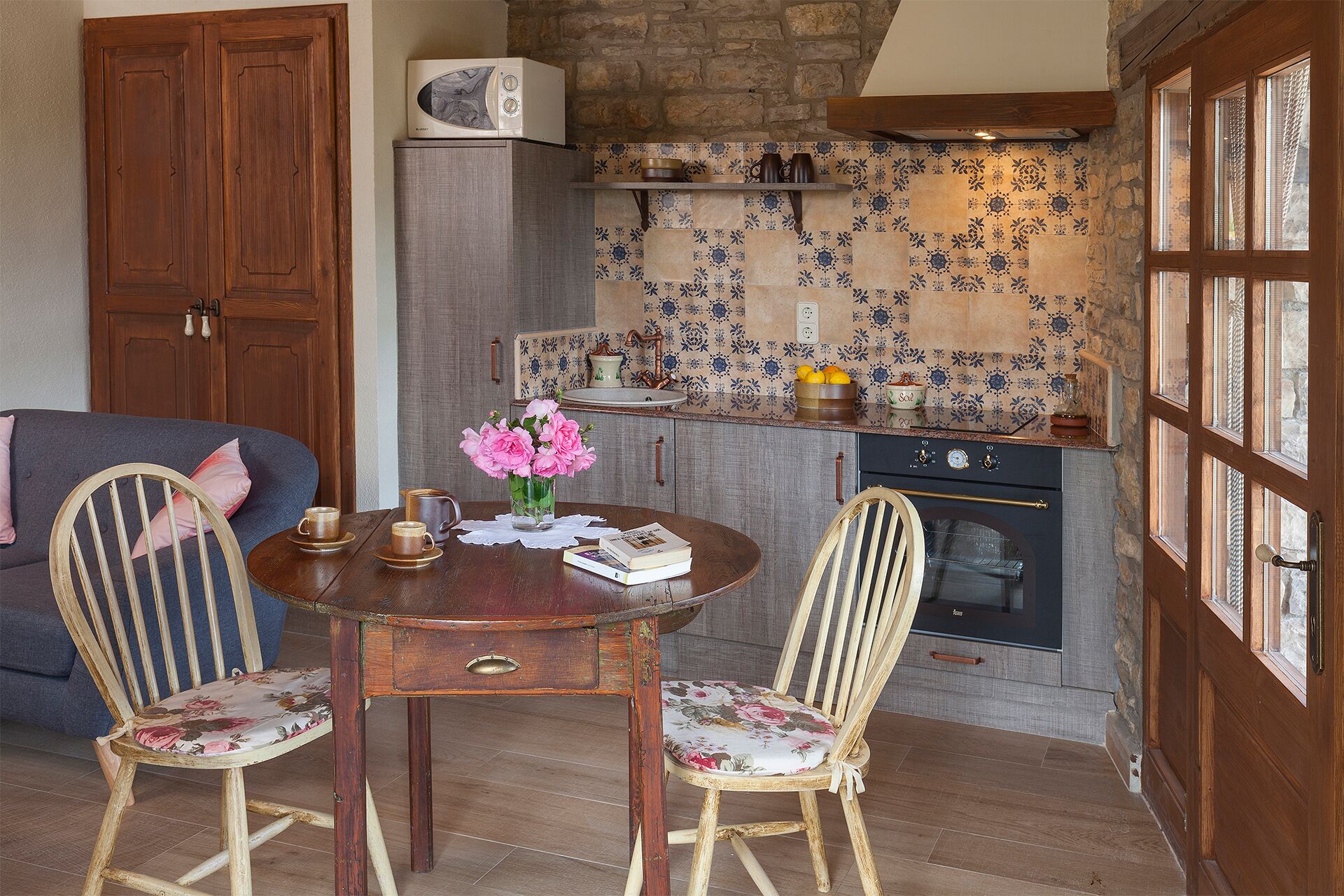 Una cocina acogedora con salpicadero de pared de piedra, armarios de madera y horno empotrado.