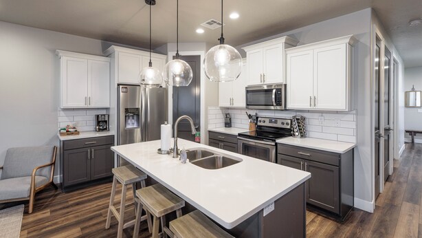 A modern kitchen with white cabinets, stainless steel appliances, and a central island with stools. - Steps to Pool - Modern 3BR Golfside w/ Fire Pit (St. George)