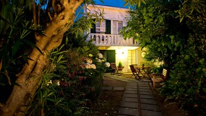 A garden pathway leading to a building with a balcony, surrounded by lush greenery and flowering plants. - Quinta das Buganvílias (Horta)