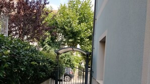 Ein schmaler Steinweg führt zu einem verschlossenen Eingang mit einem Metallbogen.
