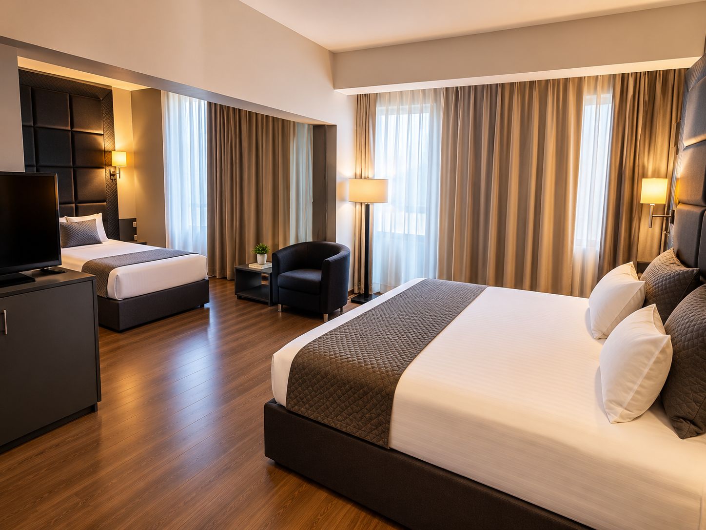 A hotel room with two beds, a TV, a desk, and a chair.