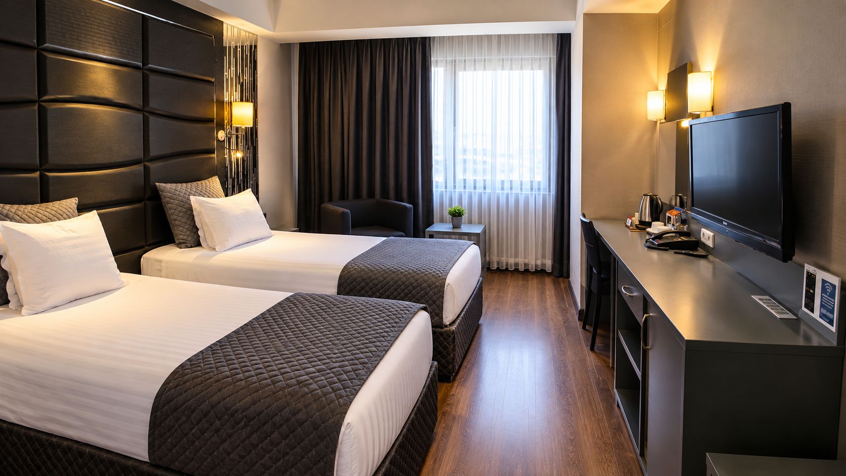 Een hotelkamer met twee bedden, een bureau, een televisie en een raam met gordijnen.