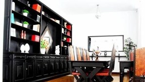 Una sala de estar moderna con un mueble negro para entretenimiento, una mesa de comedor con sillas y una pizarra en la pared.