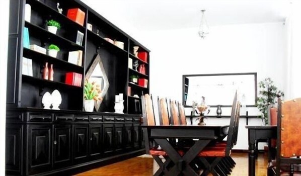 A modern living room with a black entertainment unit, a dining table with chairs, and a whiteboard on the wall. - Hotel Itararé (Itarare)