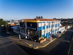 A hotel with a blue and yellow facade, a visible entrance, and a parking lot. - Hotel Itararé (Itarare)