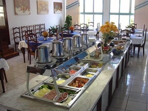A buffet setup with various food stations, including meats, salads, and fruits. - Hotel Itararé (Itarare)