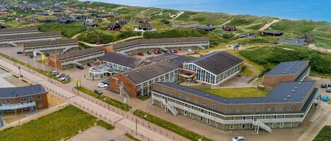 Ovenfra set udsigt over et kystnært boligområde med et stort kompleks, der inkluderer en skole og flere huse.