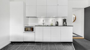 A modern kitchen with white cabinetry, a built-in oven, a coffee maker, and a wine bottle on the counter. - Awesome apartment in Ringkøbing (Ringkøbing)