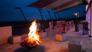 An outdoor seating area with a fire feature, tables, and chairs. - The Nest Boutique Hotel (Naivasha)