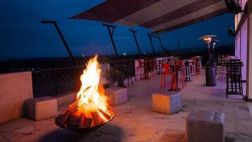 An outdoor seating area with a fire feature, tables, and chairs.