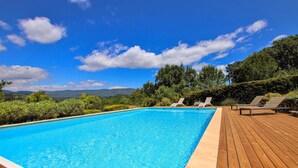 Una piscina rectangular con agua azul cristalina, rodeada por una terraza de madera.