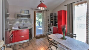 Una cocina compacta con un lavamanos, armarios rojos y un comedor con mesa y sillas.