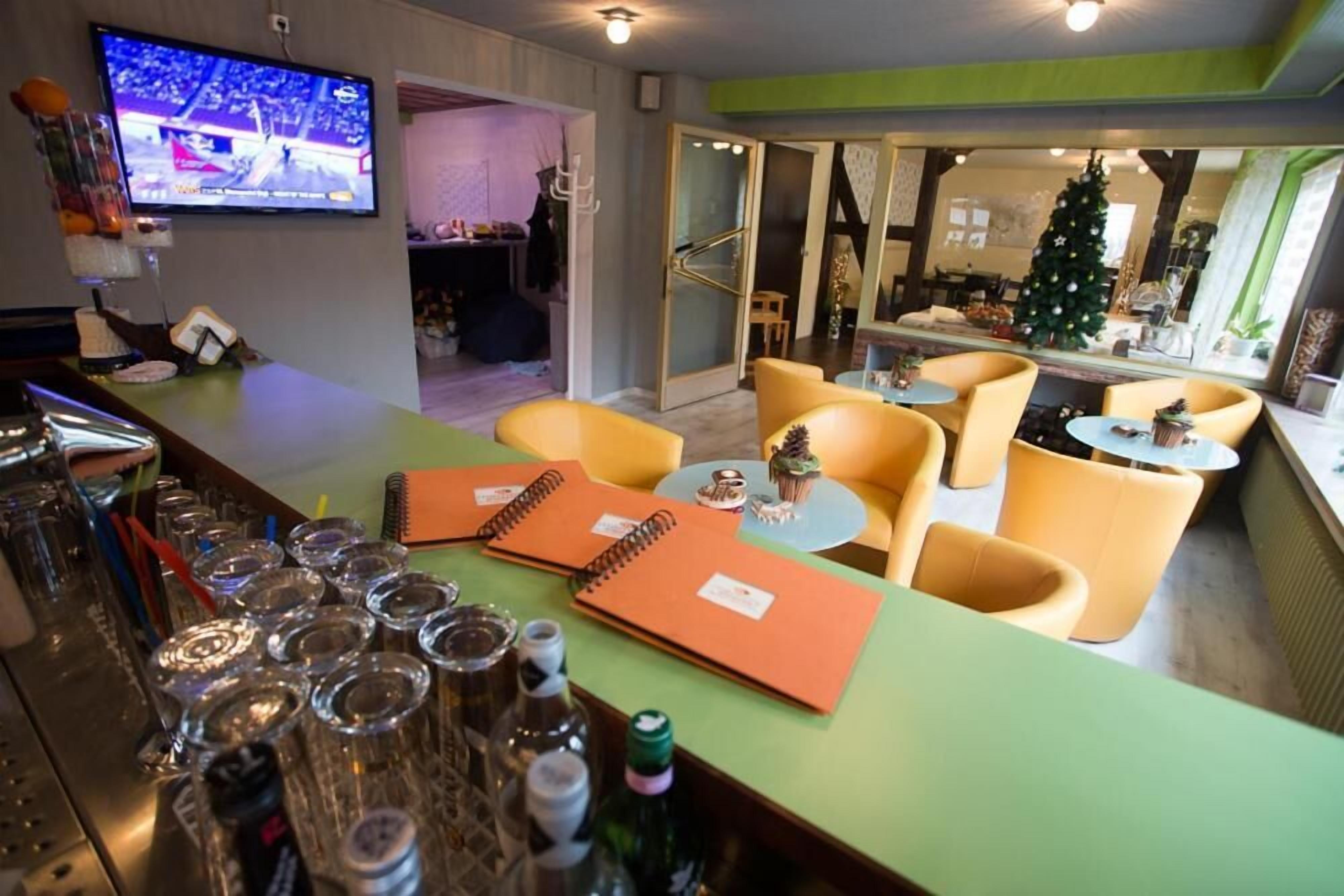 Zona de bar con mostrador, vasos y una televisión mostrando un evento deportivo.