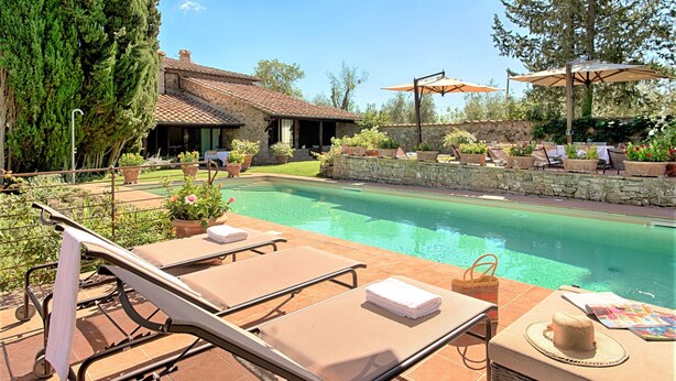 A poolside area with lounge chairs, a stone wall, and potted plants. - Luxury Villa in Chianti with Winery up to 10pax (Castellina in Chianti)