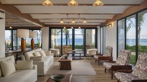 A spacious living area with a view of the ocean, featuring a sofa, chairs, a coffee table, and pendant lighting. - Ocean Eden Bay - Adults Only - All inclusive (Falmouth)