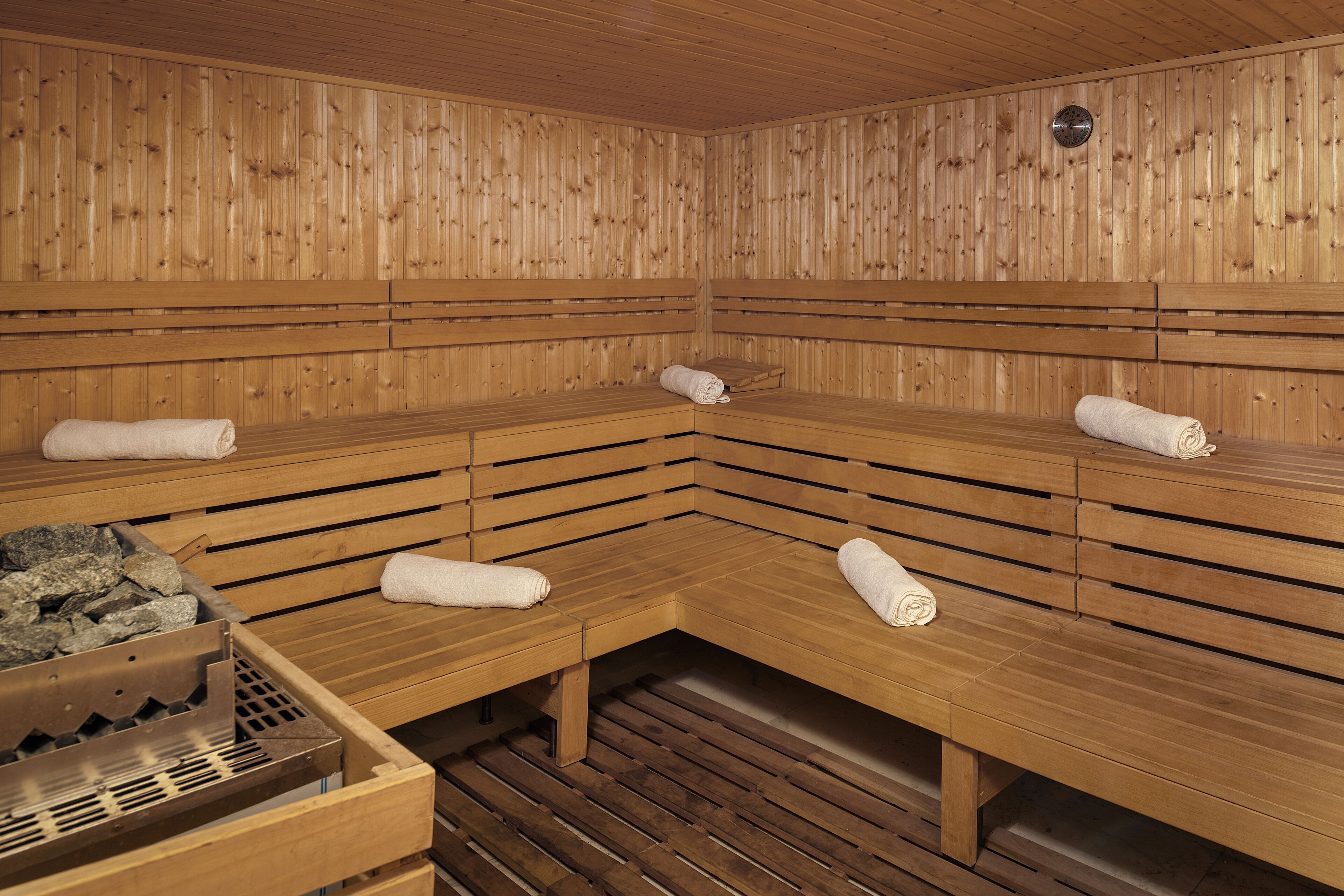 A sauna with wooden benches and benches, a bench with a towel, and a bench with a towel on the floor.
