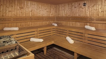 A sauna with wooden benches and benches, a bench with a towel, and a bench with a towel on the floor.