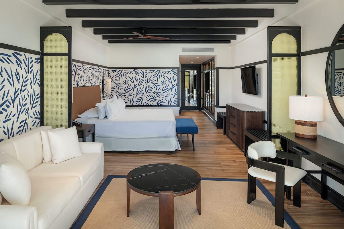 Une chambre d’hôtel comprenant un lit, un canapé, un bureau, une chaise et un téléviseur.