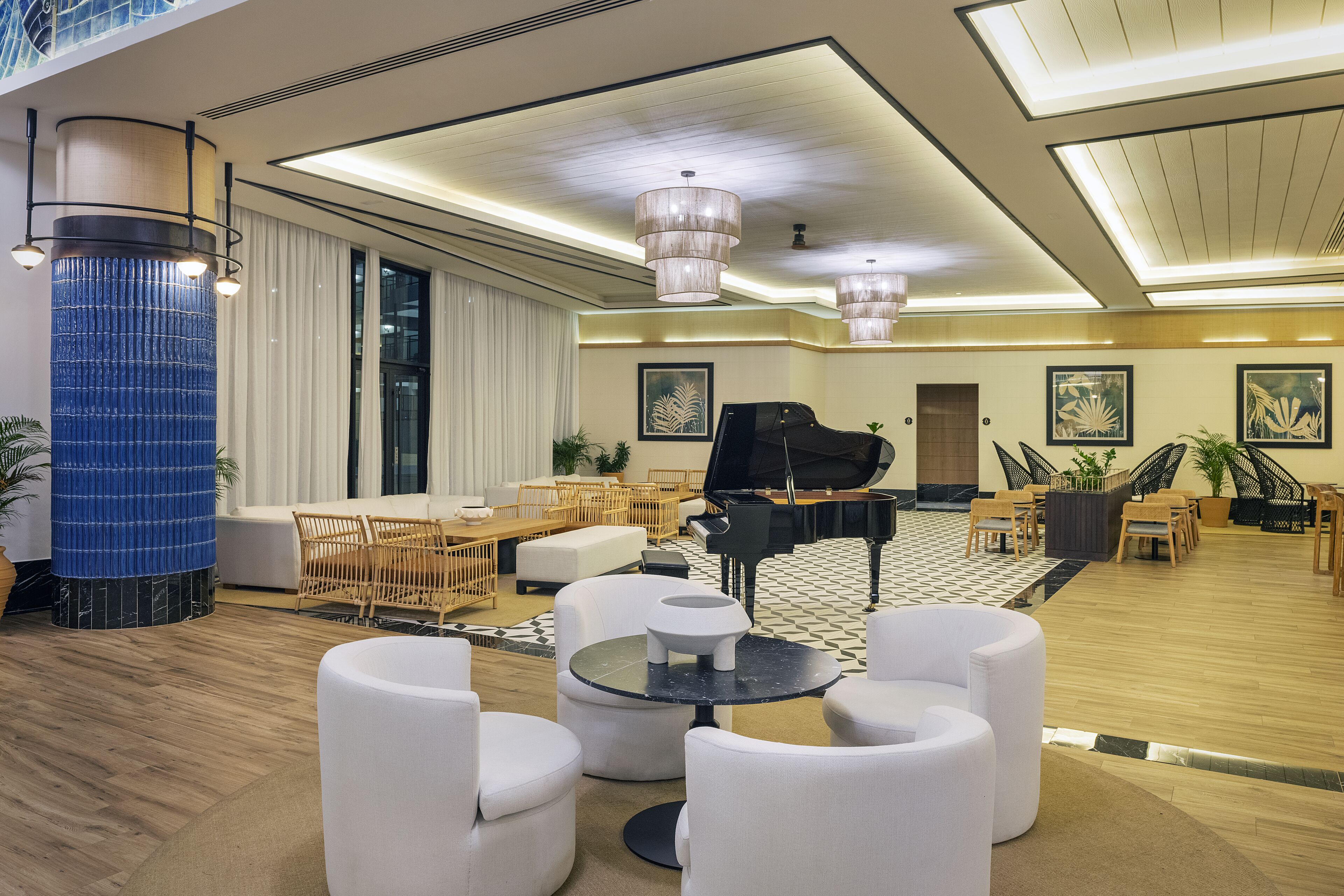 Um hall espaçoso com um piano de cauda, assentos confortáveis e um grande pilar azul.