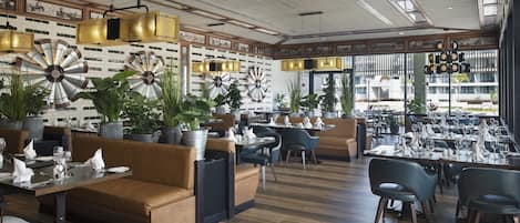 A restaurant with wooden flooring, leather seating, and decorative wall sconces.