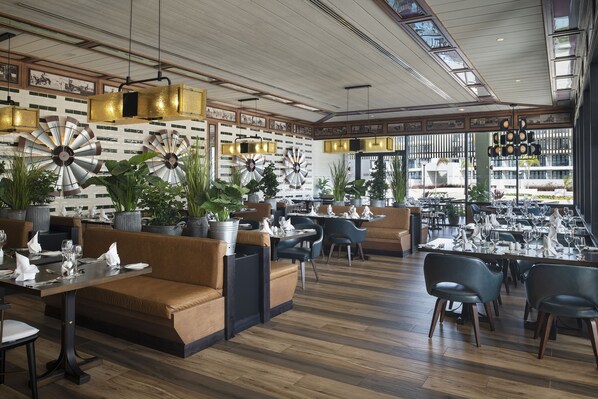 A restaurant with wooden flooring, leather seating, and decorative wall sconces.