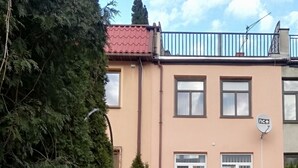 A residential building with a brick pathway leading to the entrance, surrounded by greenery and trees.