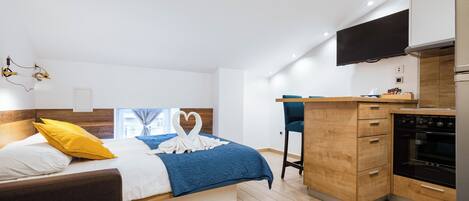 Une chambre moderne avec un lit, un bureau et un coin cuisine.