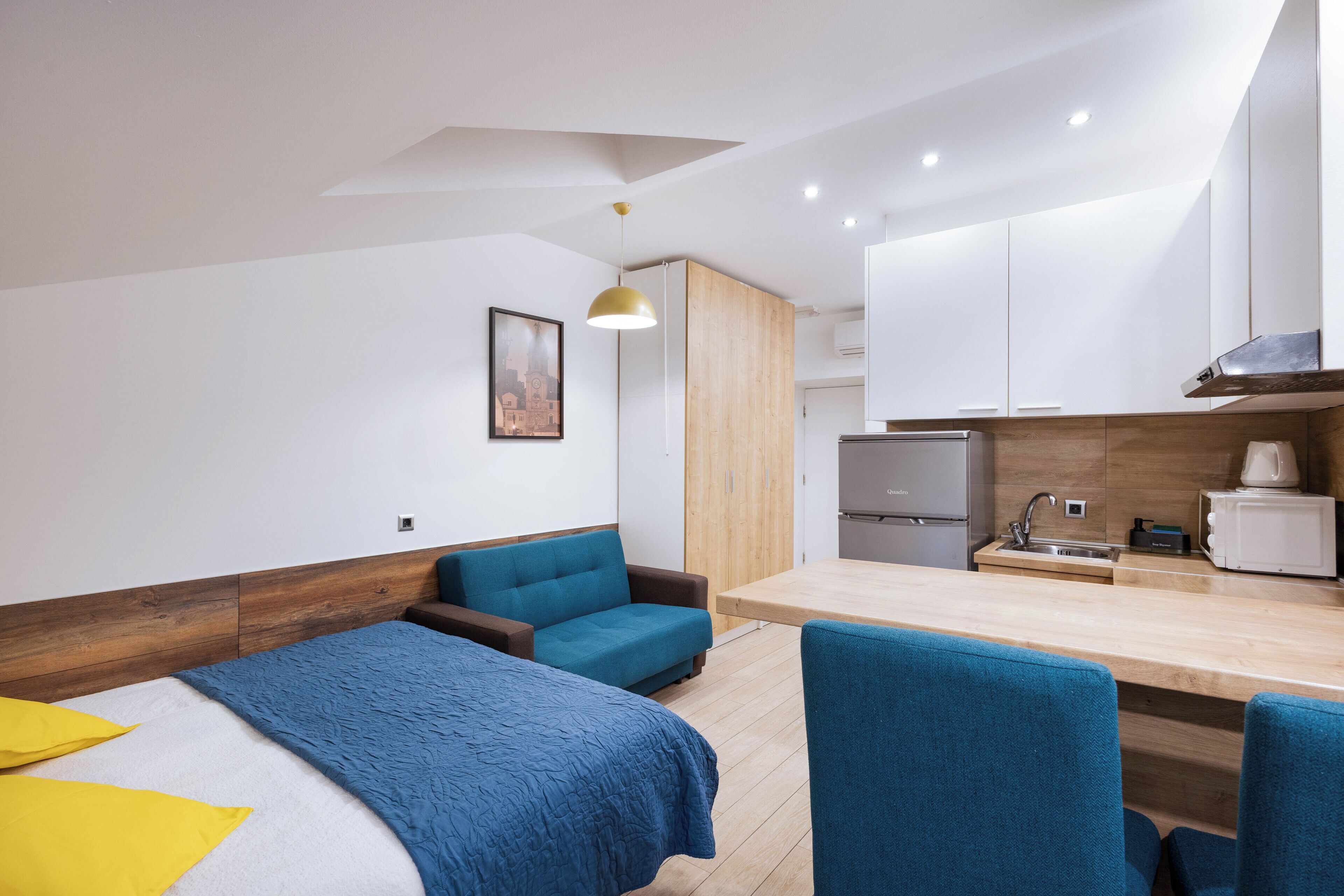 Une chambre d’hôtel moderne équipée d’un lit, d’un canapé, d’une table à manger et d’une kitchenette.