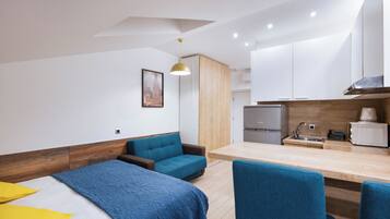 Une chambre d’hôtel moderne équipée d’un lit, d’un canapé, d’une table à manger et d’une kitchenette.
