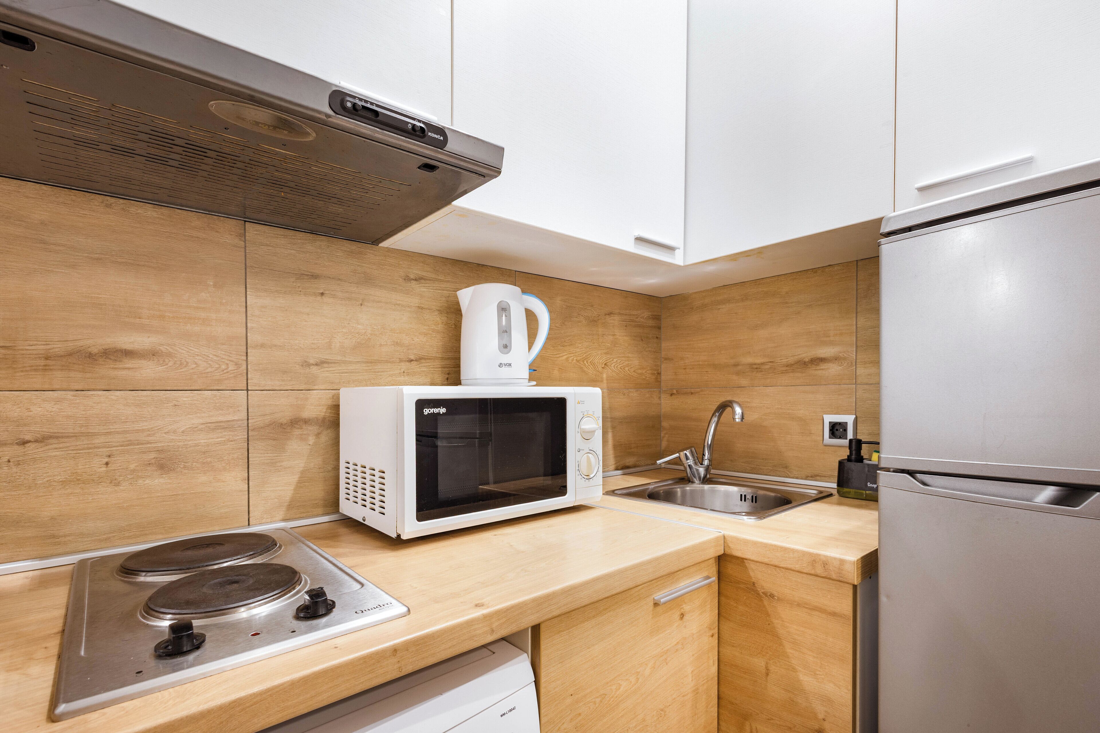 Una cocina moderna con microondas integrado, estufa y refrigerador de acero inoxidable.