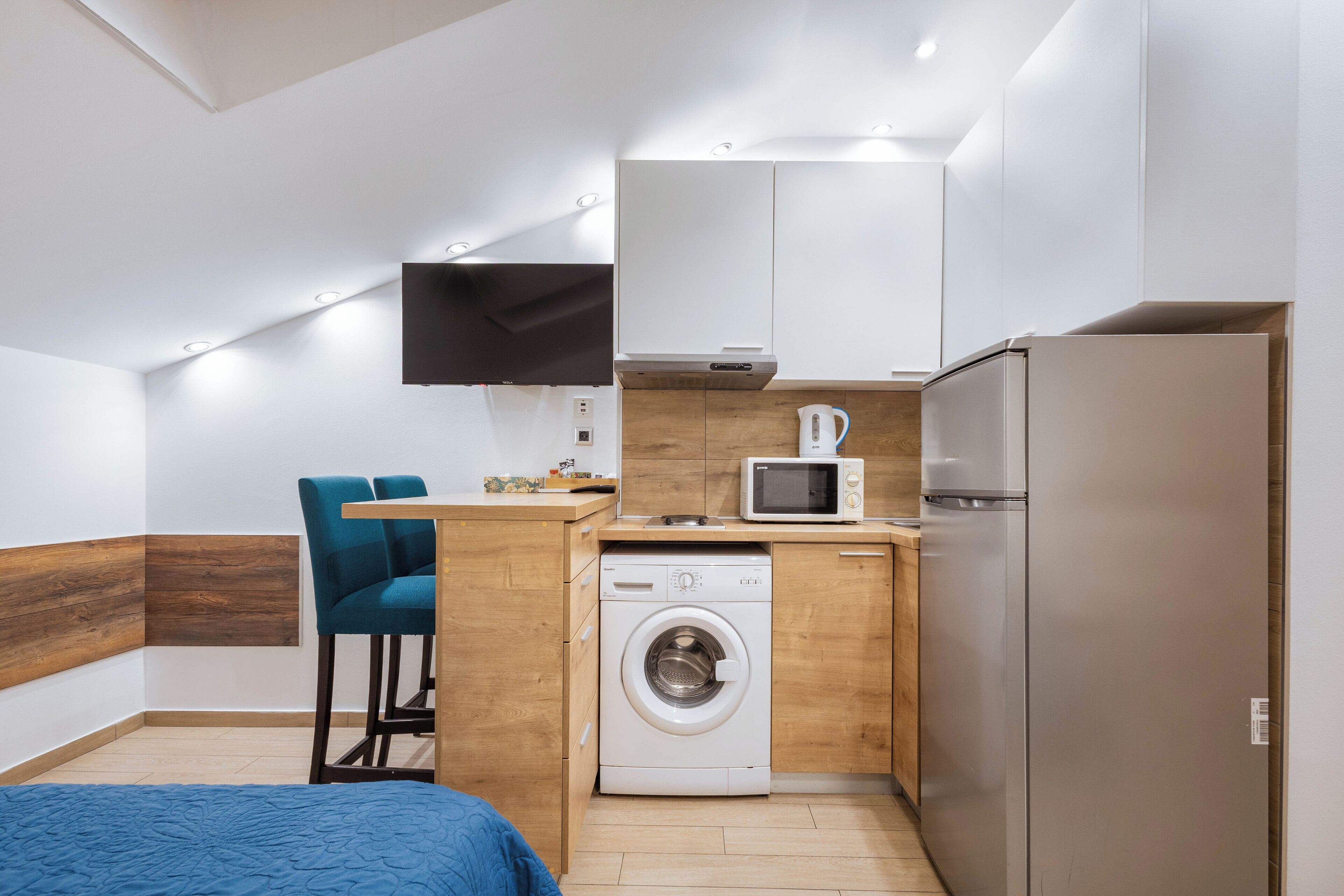 A compact kitchen with a washing machine, microwave, and refrigerator.