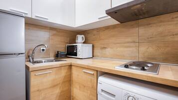 A compact kitchen with white cabinets, a microwave, a coffee maker, a sink, and a dishwasher.