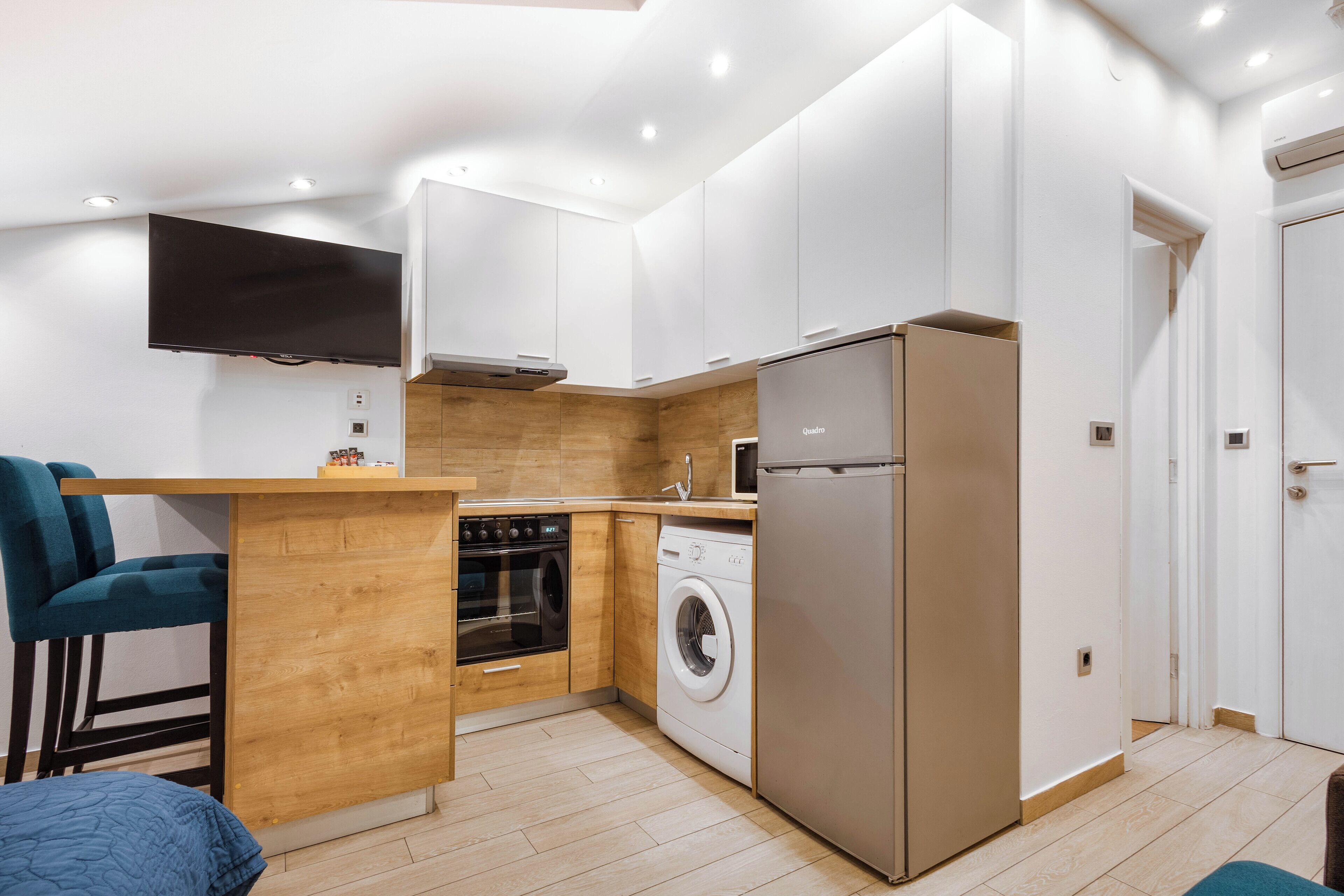 A compact kitchen with a built-in oven, microwave, washing machine, and refrigerator.