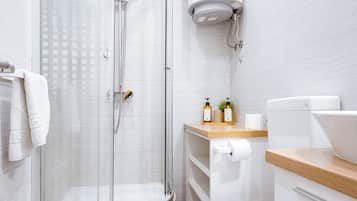 Een moderne badkamer met een douchecabine van glas, een toilet en een wastafel.