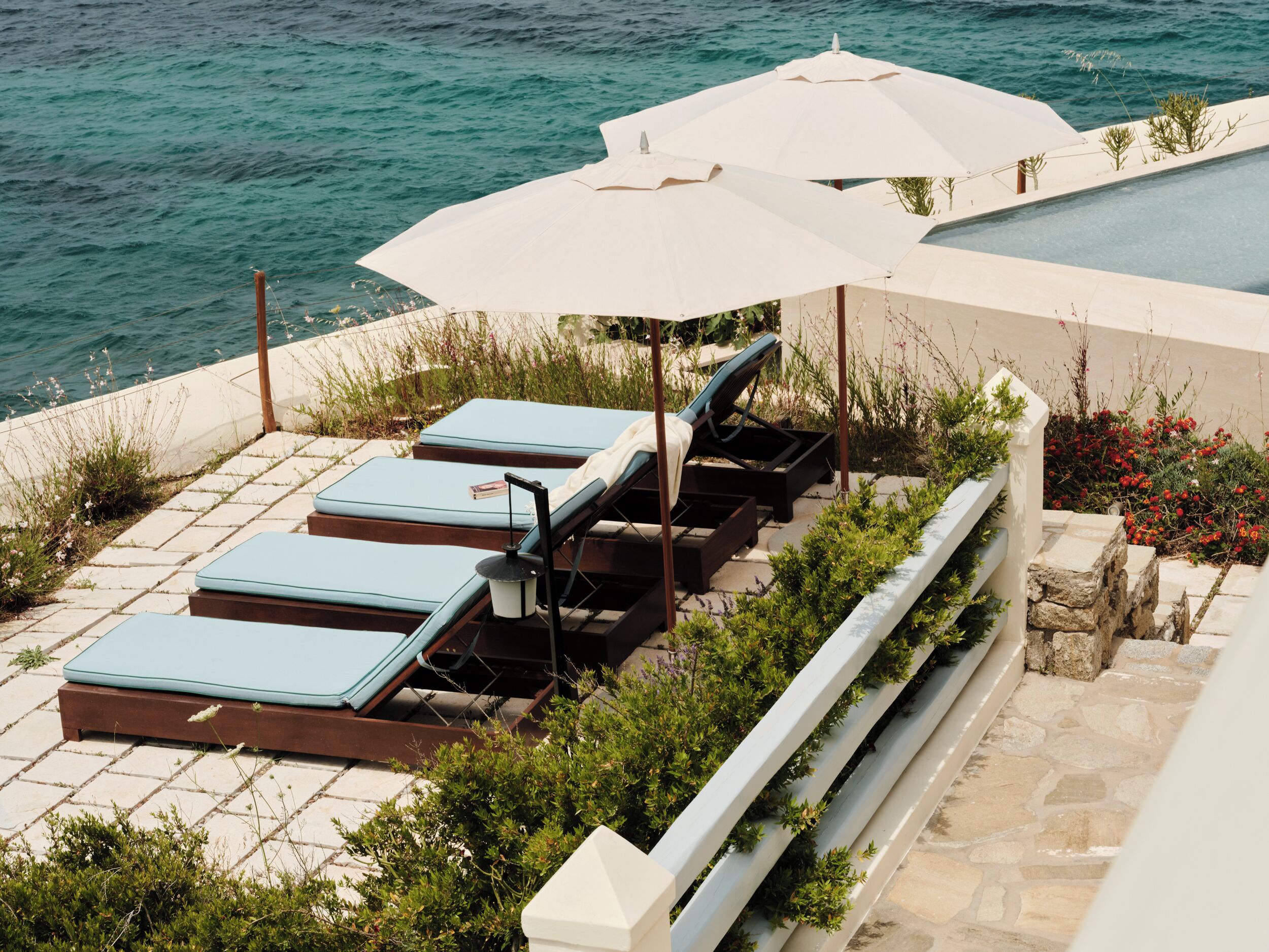 A rooftop terrace with lounge chairs and umbrellas overlooking the sea.