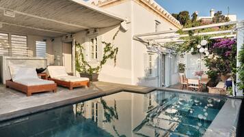 A poolside area with two wooden loungers, a small table, and a chair.