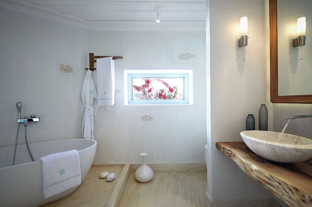 A modern bathroom with a freestanding bathtub, a large mirror, and a wooden vanity.