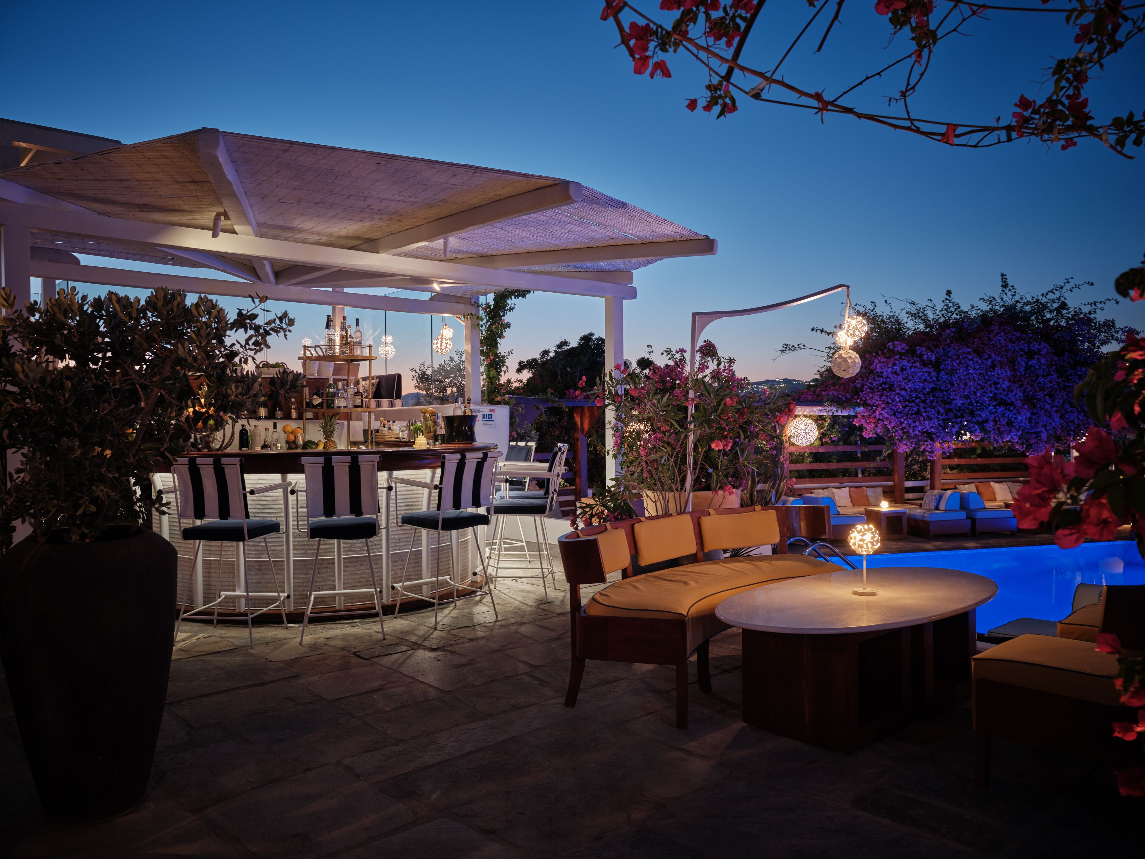 Un área de bar al aire libre con asientos y piscina.