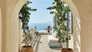 An arched pathway leading to a balcony with a view of the sea, a sofa, and potted plants. - Belvedere Hotel - The Leading Hotels of the World  (Mykonos)