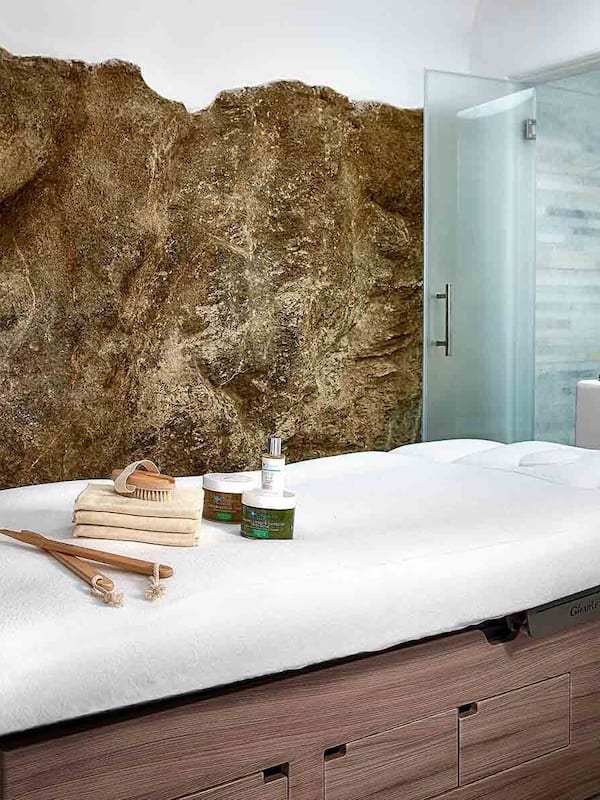 Experience the serenity of a natural oasis in this bathroom, featuring a textured rock wall and sleek, modern design.