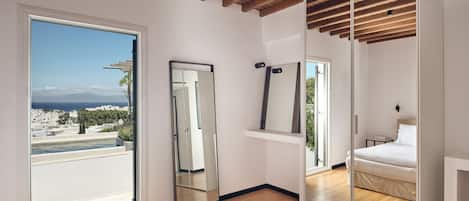 A modern bedroom with a wooden ceiling, a large mirror, a bed, and a view of a cityscape through a large window.