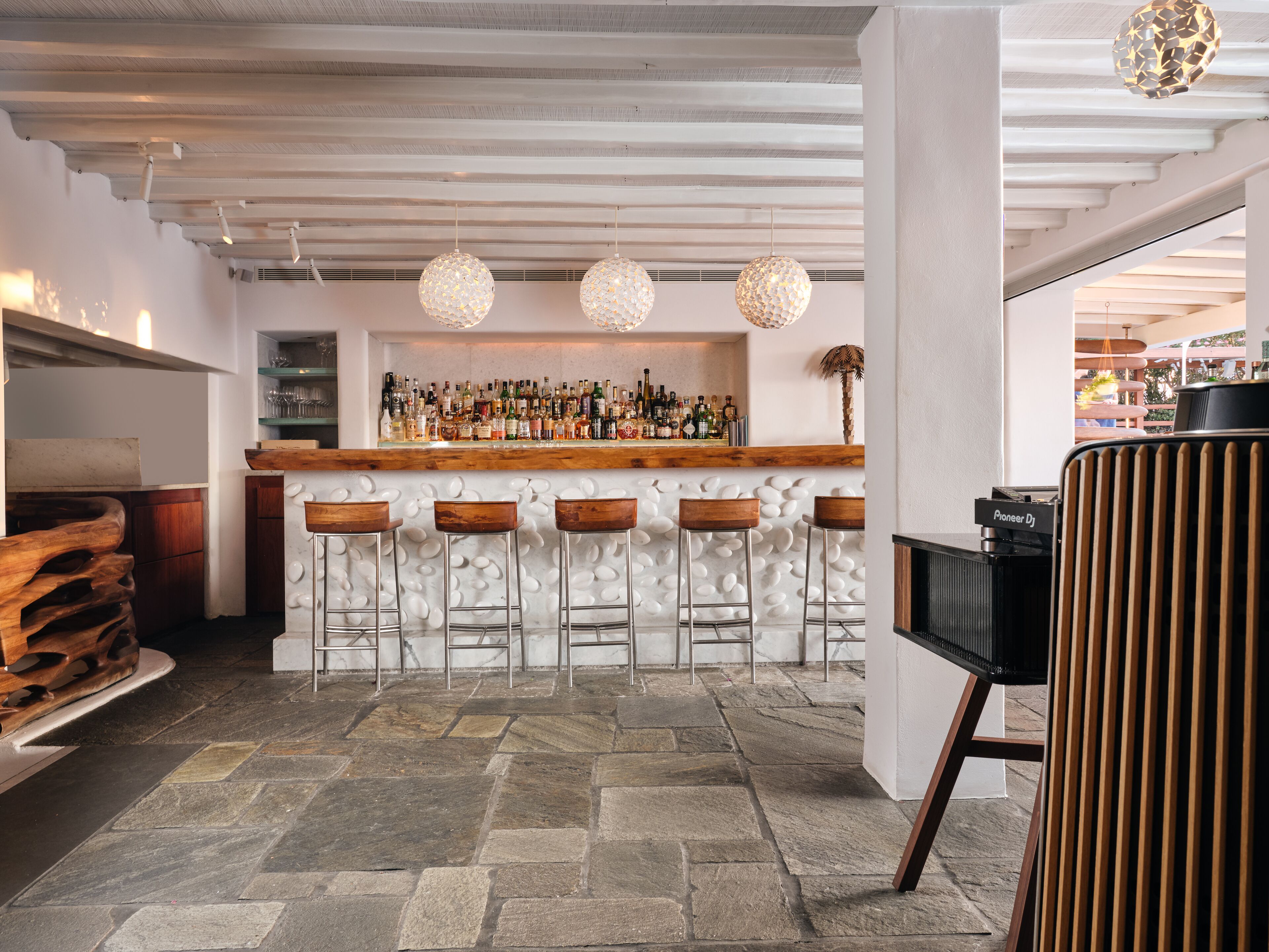 A bar area with a stone floor, wooden bar counter, and stools.