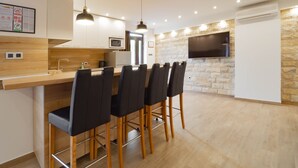 Una cocina moderna con una isla central, taburetes de bar, un microondas y un televisor de pantalla plana montado en la pared.