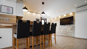 Una cocina moderna con comedor, que presenta una pared de piedra, un televisor de pantalla plana y piso de madera.