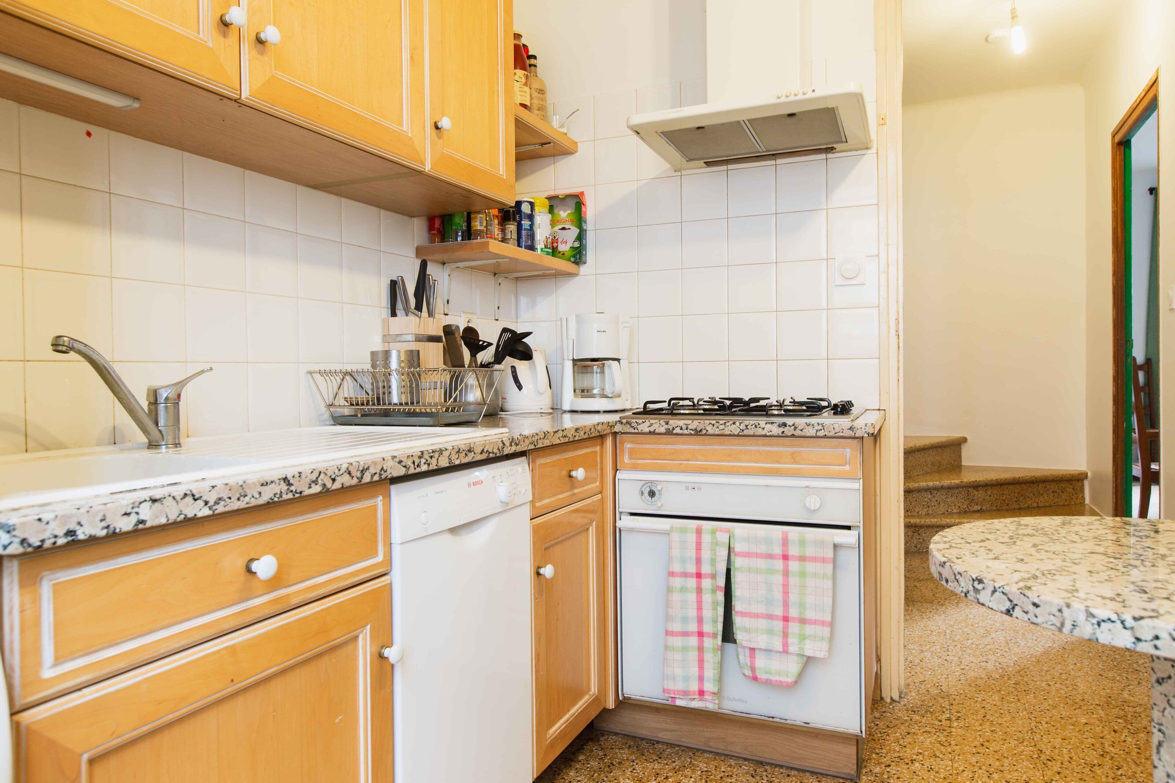 Una cocina con armarios de madera, lavavajillas, estufa y cafetera.