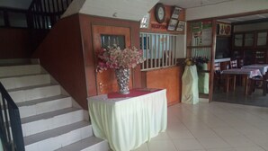 Zona de recepción con mostrador, escalera y piso de baldosas.