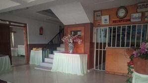 Un área de recepción con una escalera, un mostrador y un reloj en la pared.
